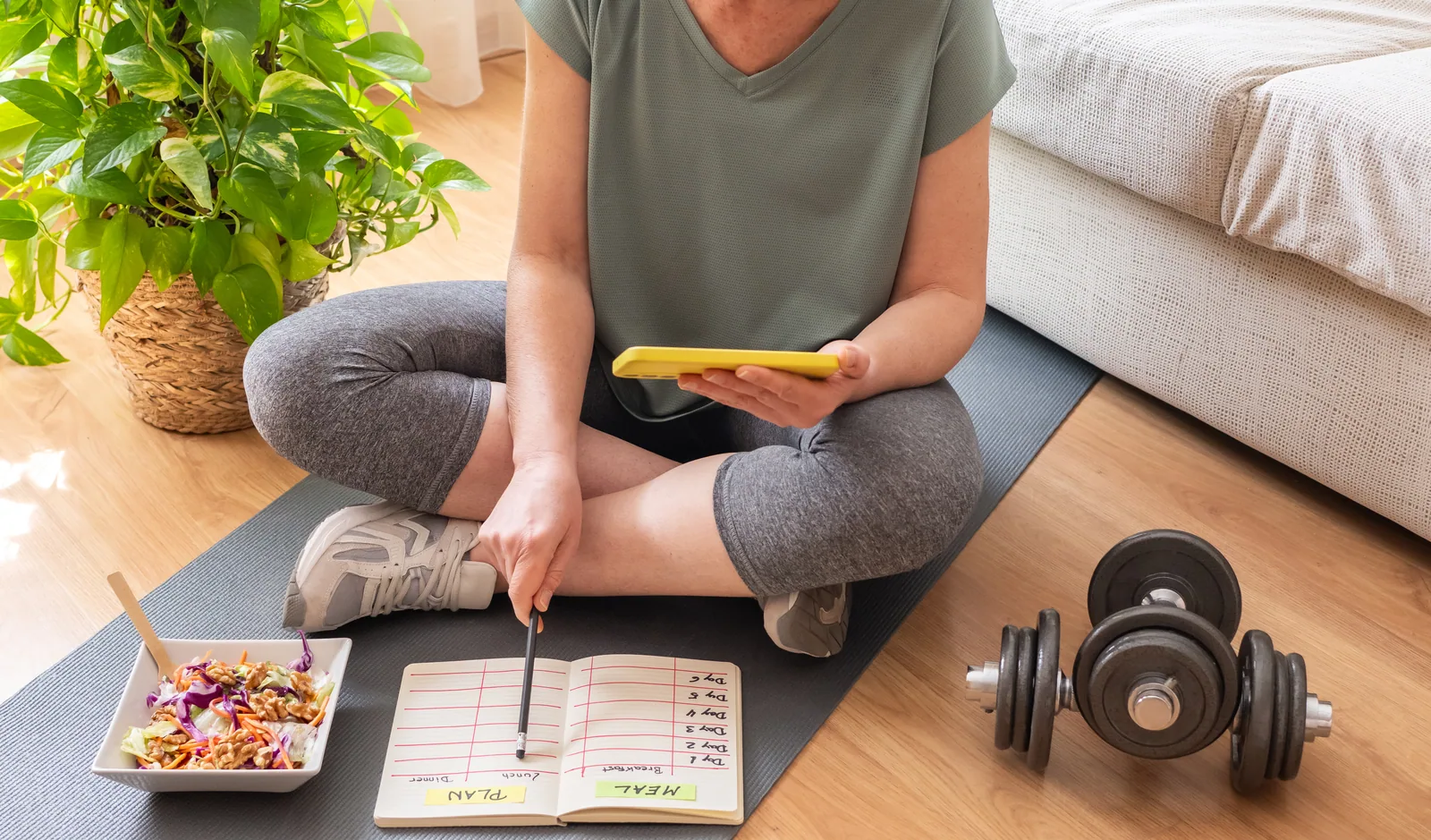 Woman planning workouts in a notebook at home
