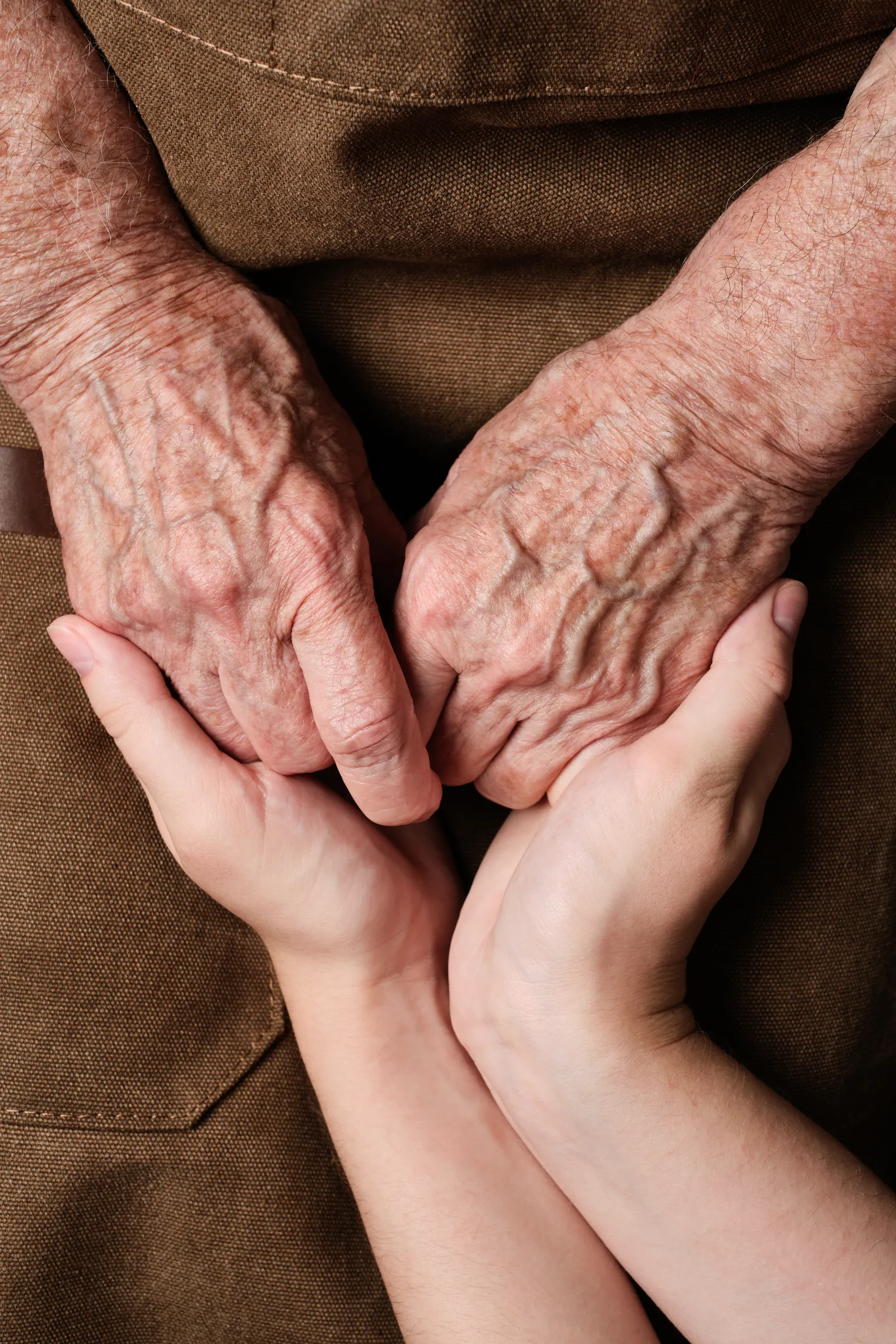 Younger hands holding an older person’s hands