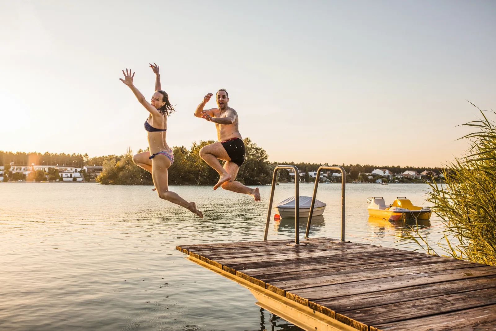 People jumping off a dock into a lake